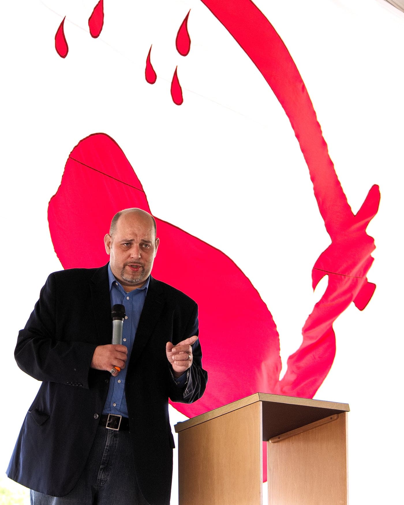Daniel Miller speaking in front of a large Goliad flag, the 1835 Texas Revolution independence banner